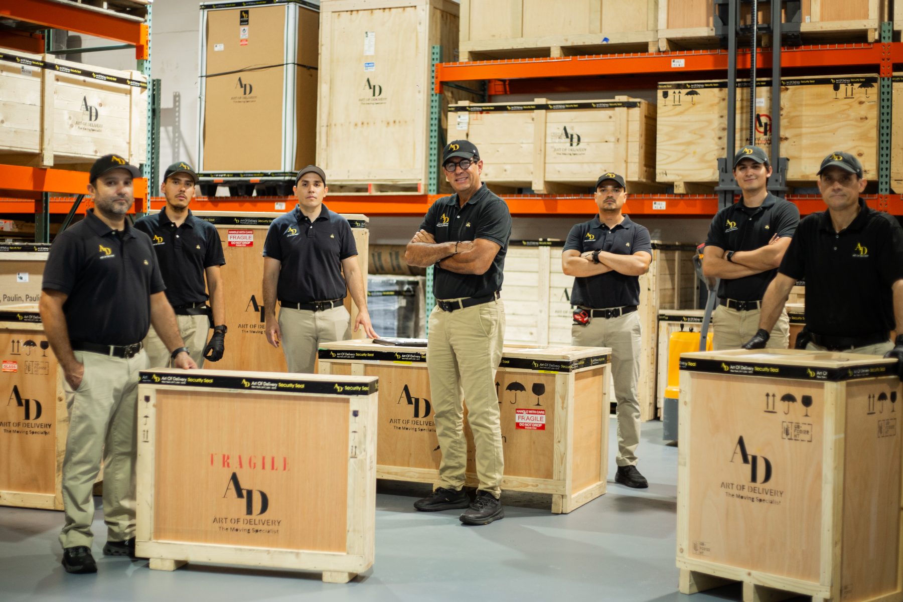 The Art of Delivery team standing among branded crates in the warehouse