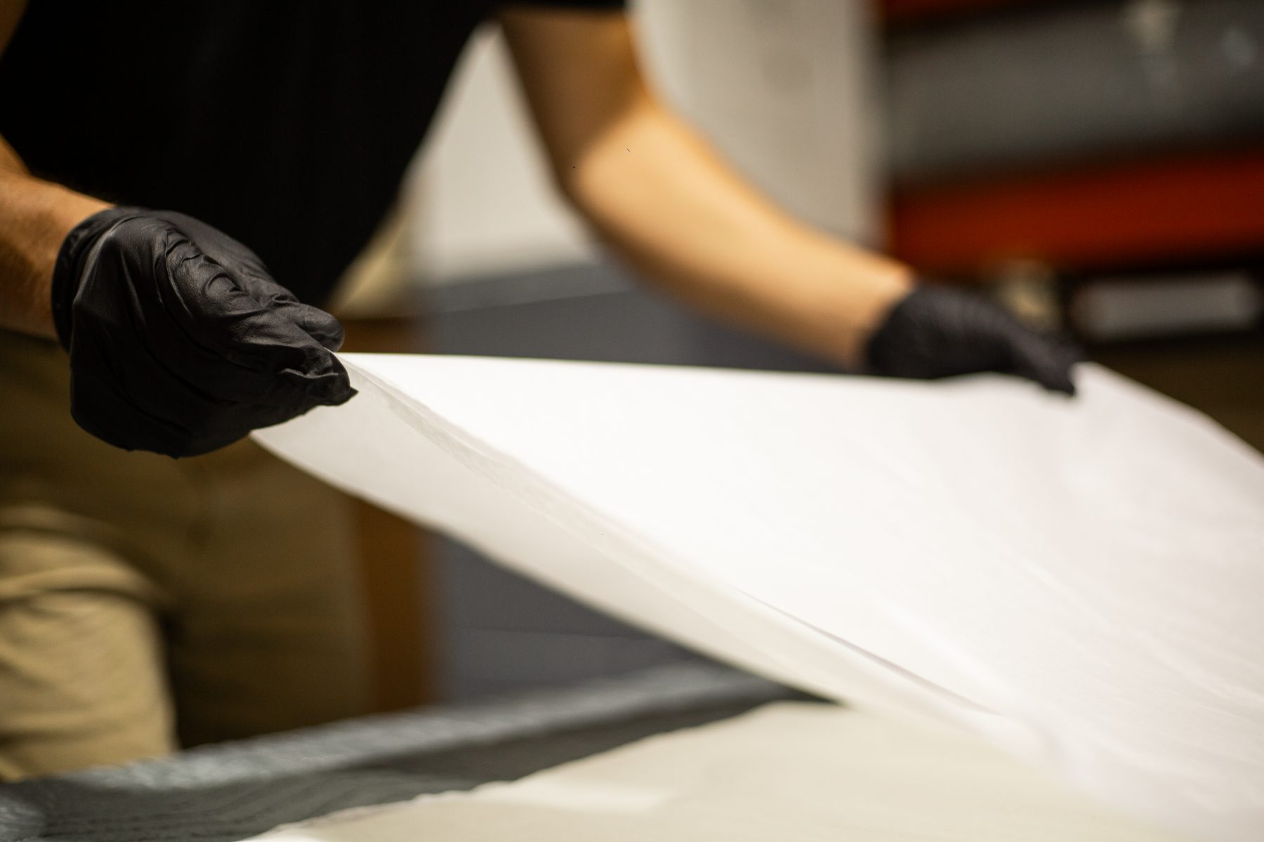 Gloved hands smoothing protective packing paper