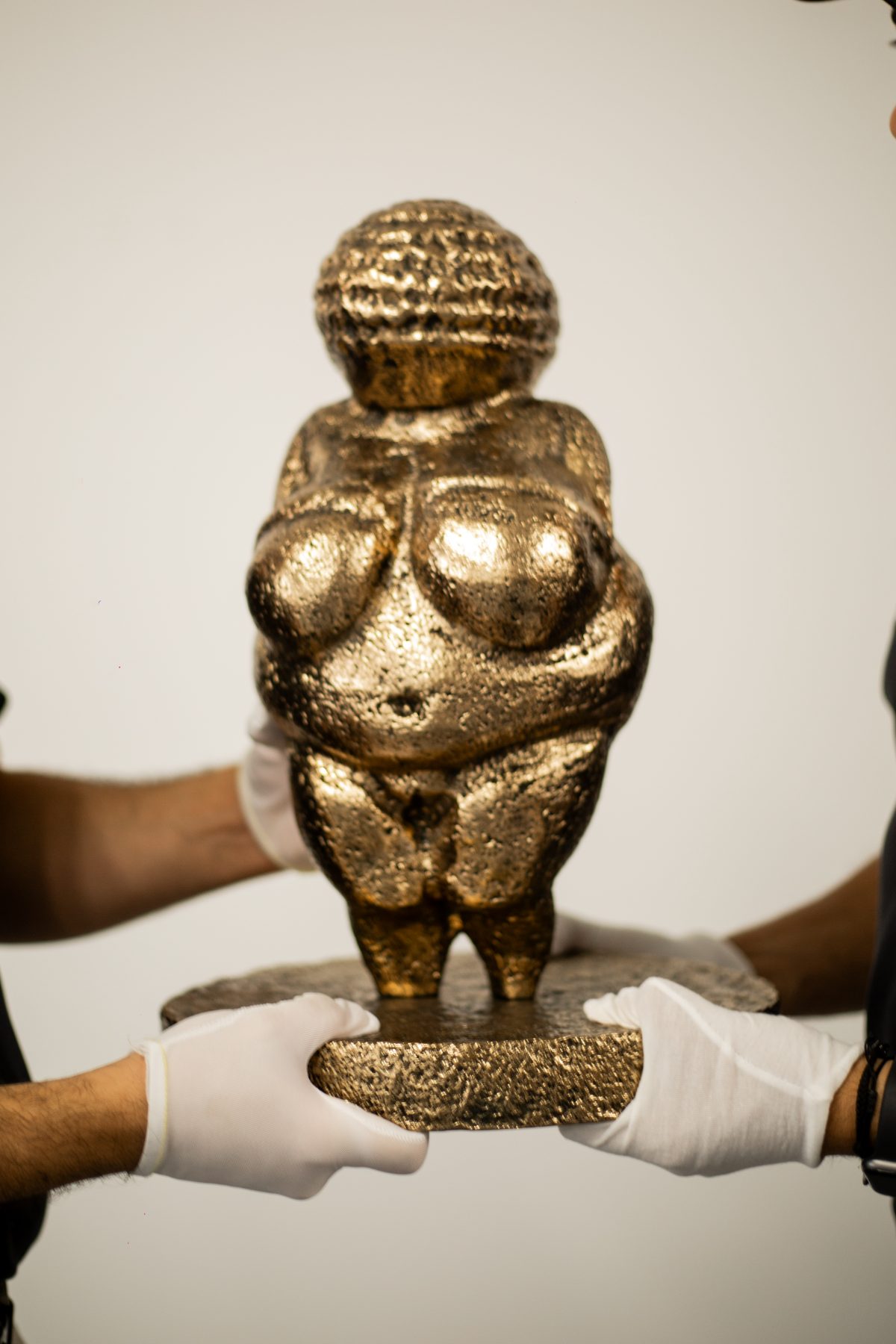 White-gloved hands handling a gilded sculpture