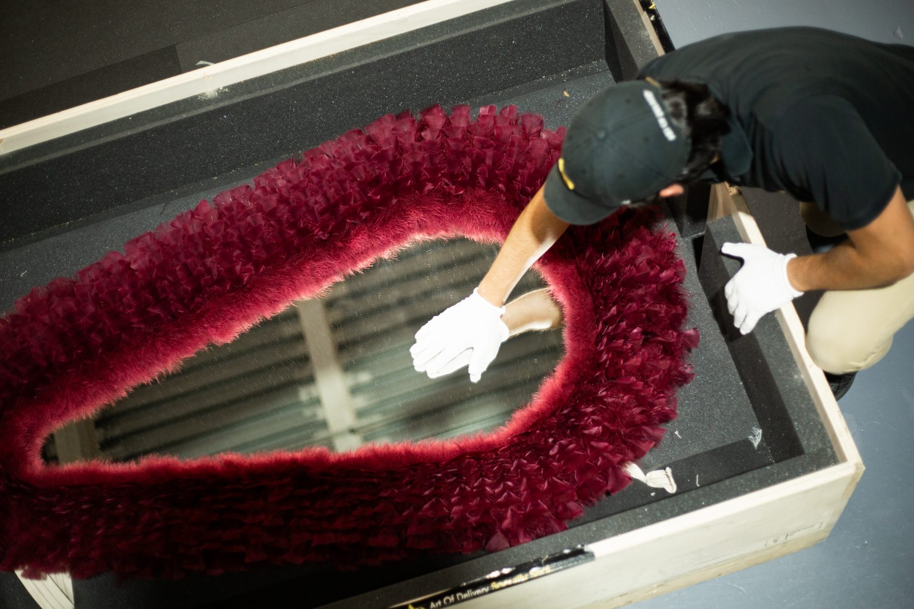 White-gloved specialist uncrating a feathered mirror