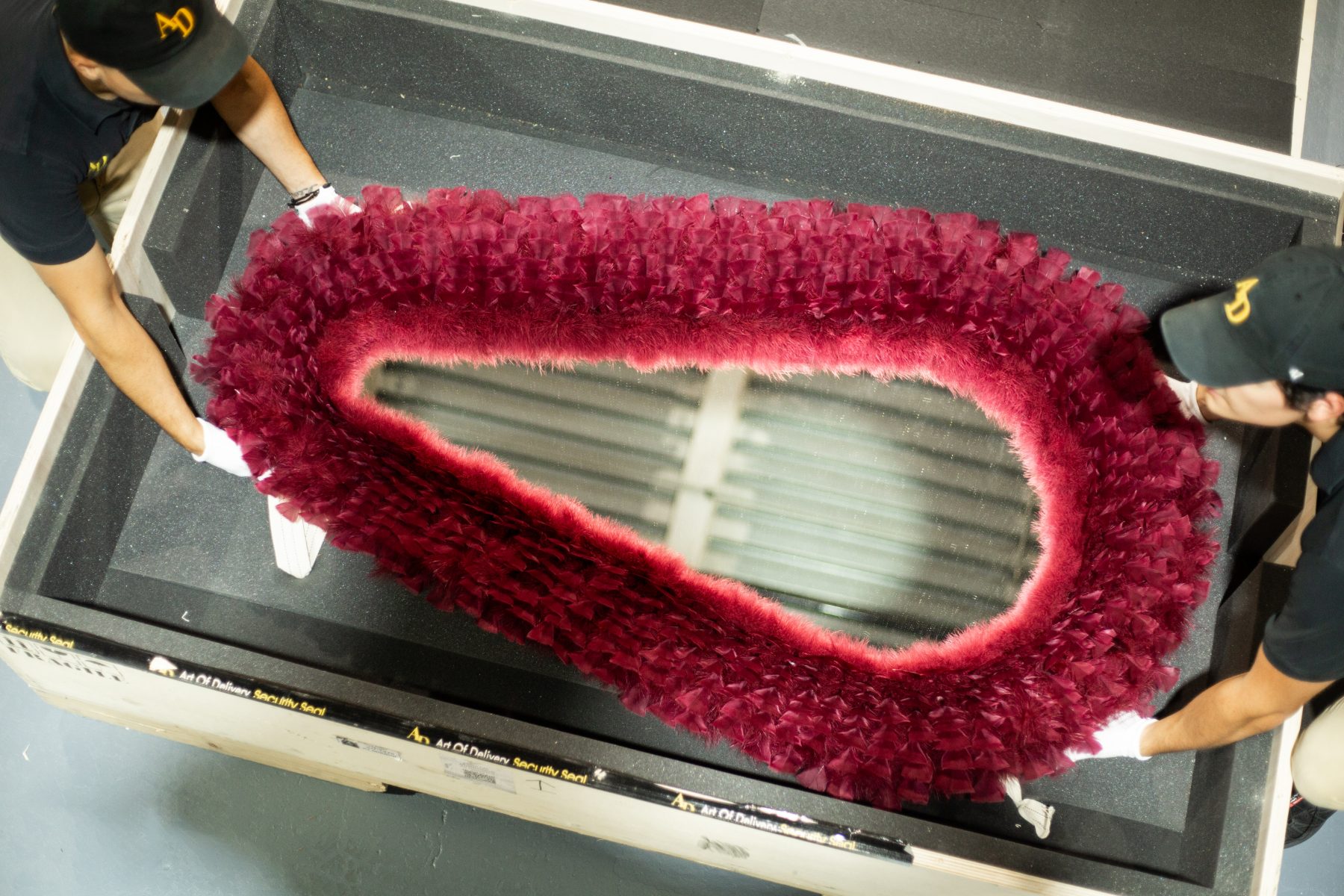 Crew lowering a feathered mirror into a foam-lined crate