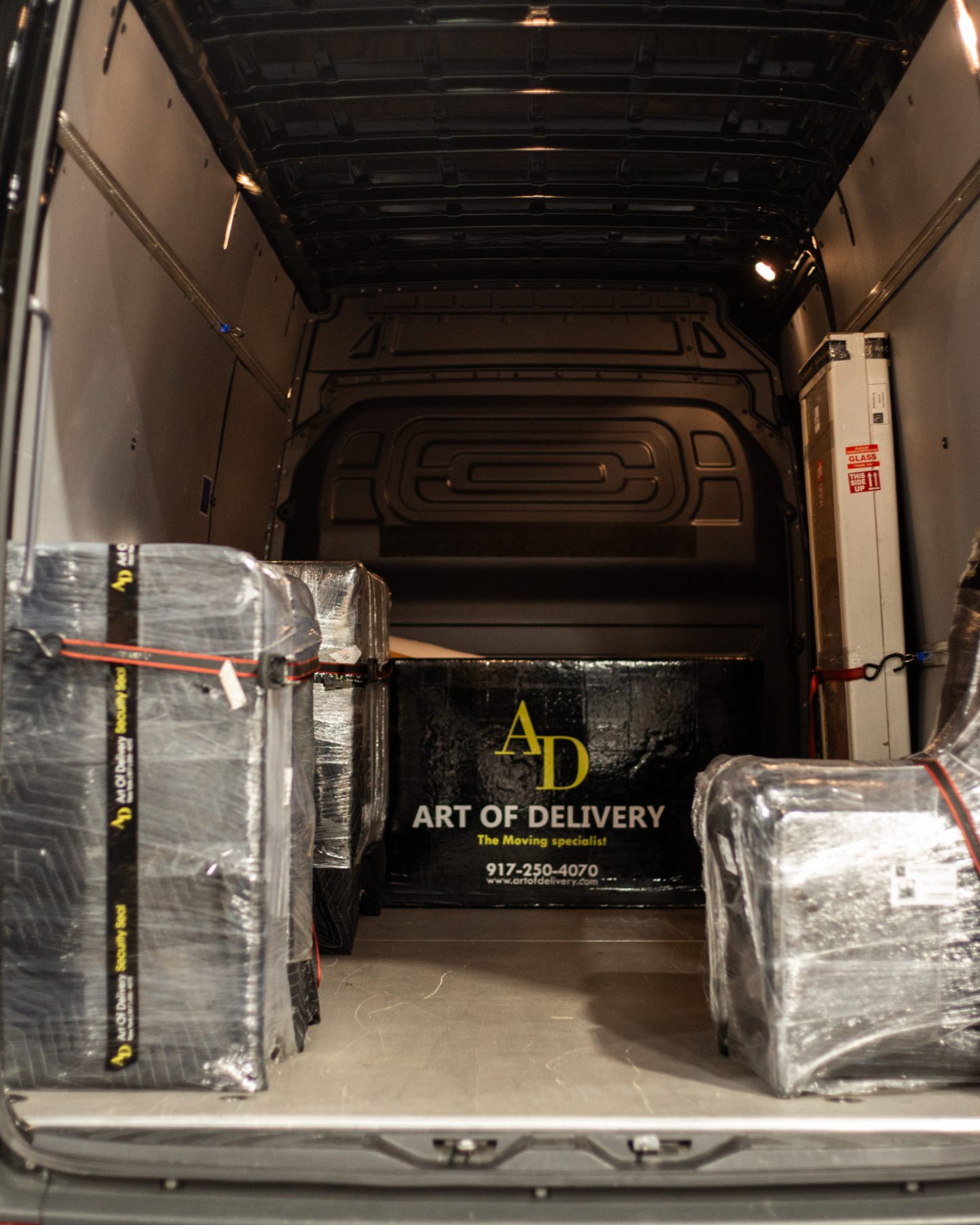 Wrapped and strapped pieces loaded inside an Art of Delivery van, doors open